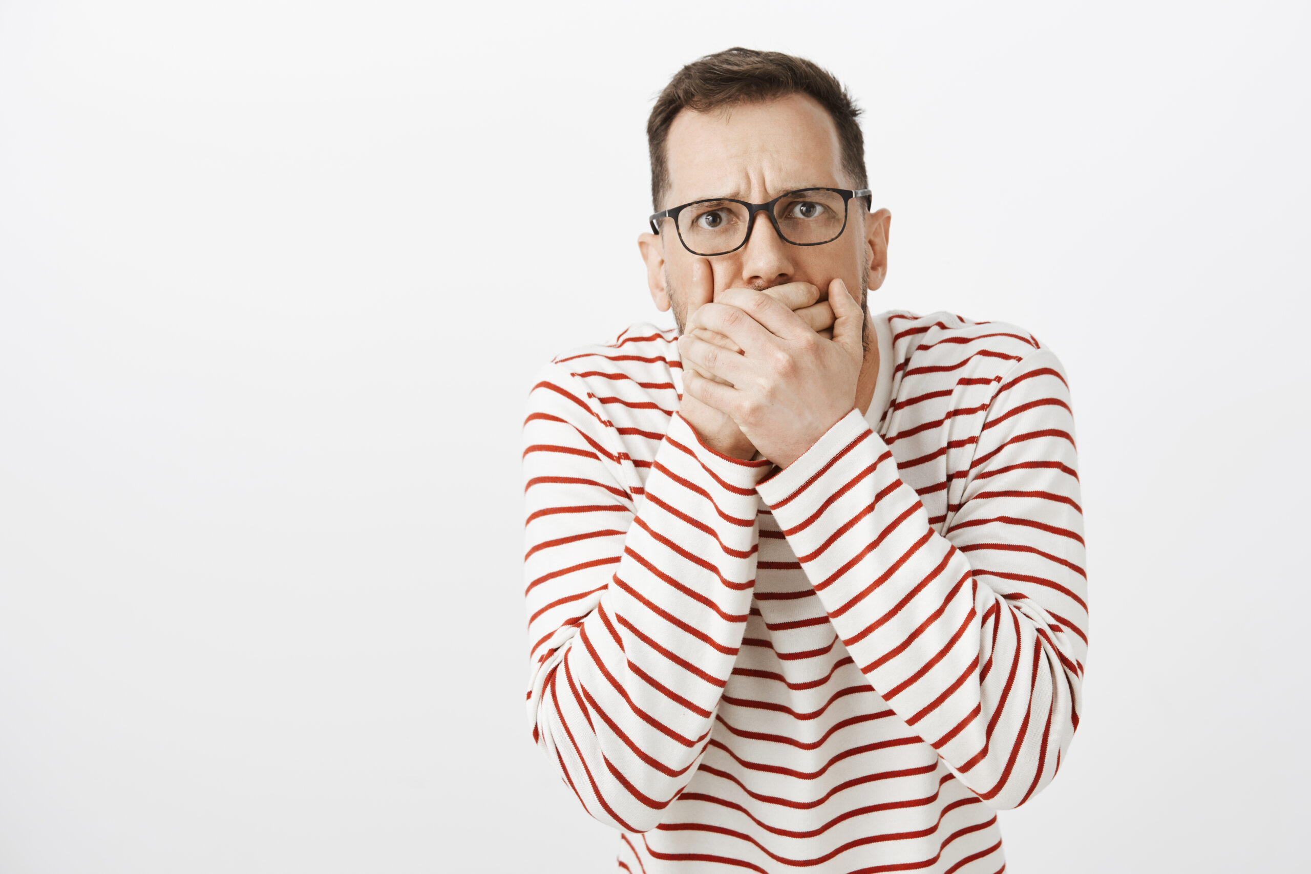 Guy want throw up tasting awful food. Portrait of displeased european boyfriend in black glasses, covering mouth with both palms and frowning, suffering from stomachache and wanting vomit. Health problem concept